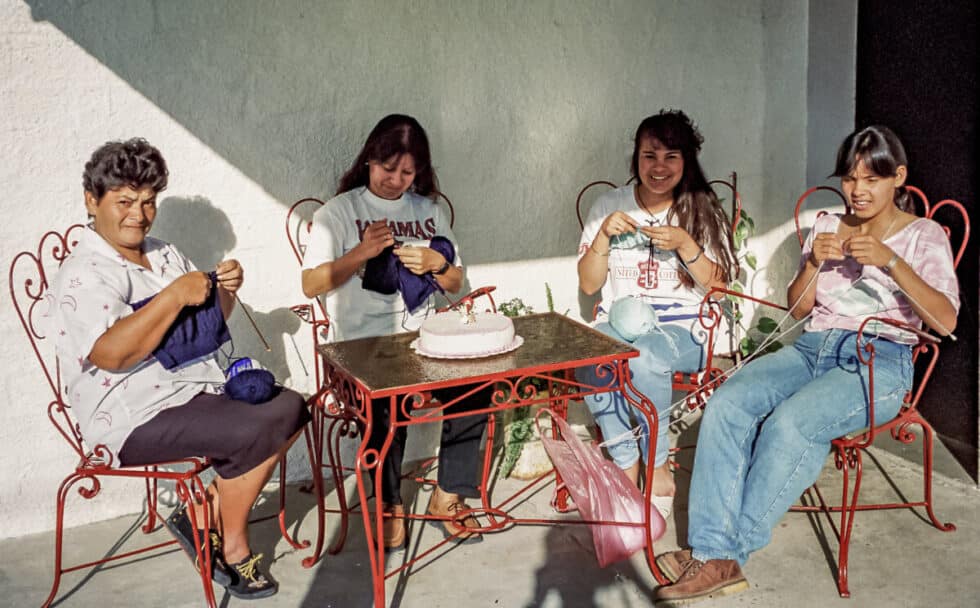 Four women sitting around a table with a cake knitting sweaters. A Peace Corps volunteer’s story in Baltasar Brum, Uruguay.