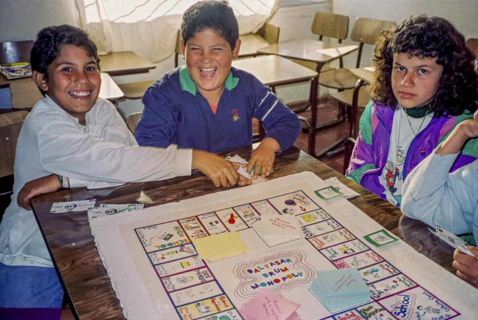 Three elementary age students playing a homemade game called Baltasar Brum Monopoly. A Peace Corps volunteer’s story in Baltasar Brum, Uruguay.