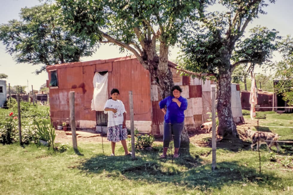 Woman and girl standing outside their home made of corrugated tin. A Peace Corps volunteer’s story in Baltasar Brum, Uruguay.